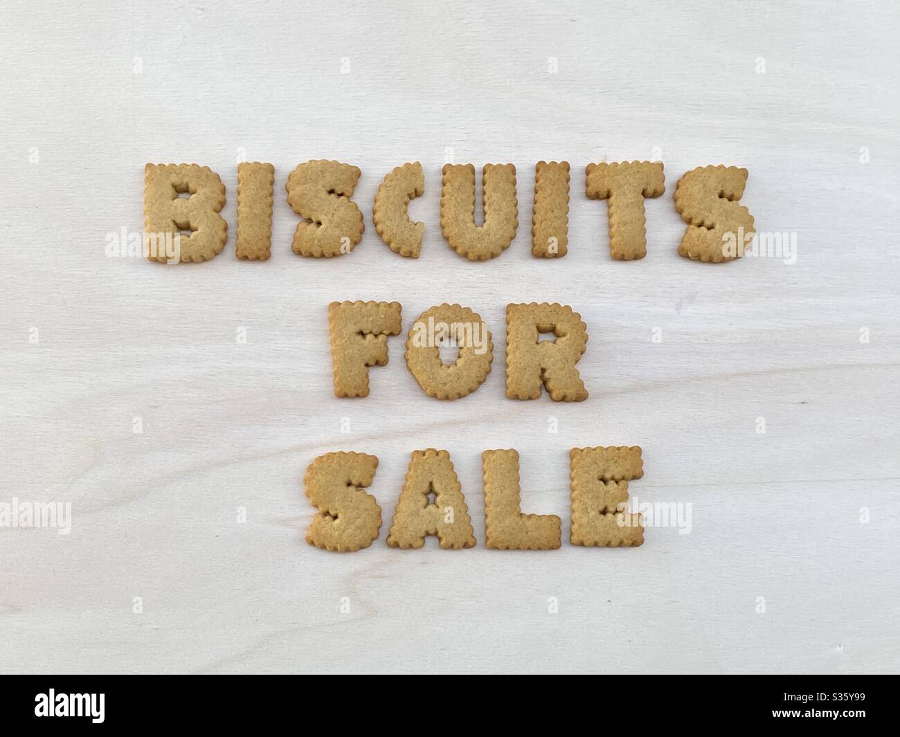 Kekse zu verkaufen, kreative Werbeidee mit einer Komposition von Cookie-Buchstaben über weißem Holz Stockfoto