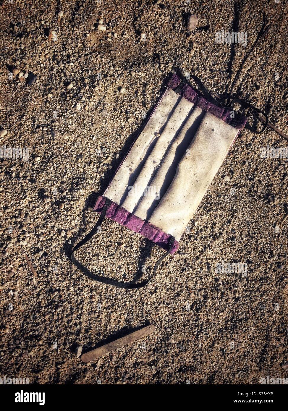 Covid 19 schmutzige Schutzmaske auf dem Boden - Smartphone-aufgenommenes Stockfoto