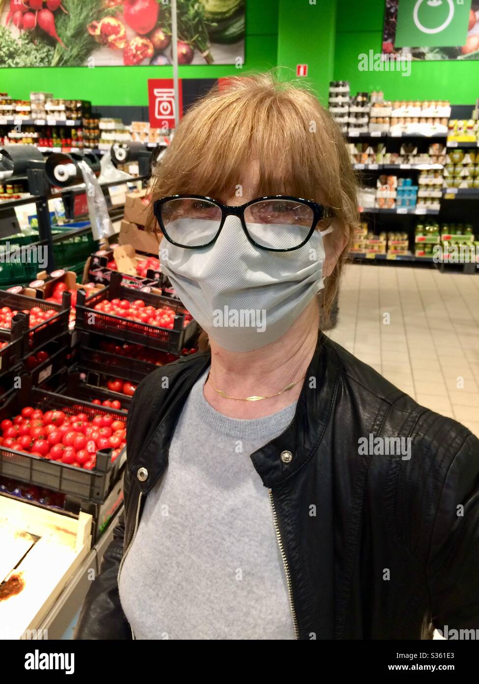Ältere Frau mit großer Schutzmaske und Brille beim Einkauf in der Gemüseabteilung in einem Supermarkt während der Ausbreitung des Covid-19 Coronavirus. Stockfoto