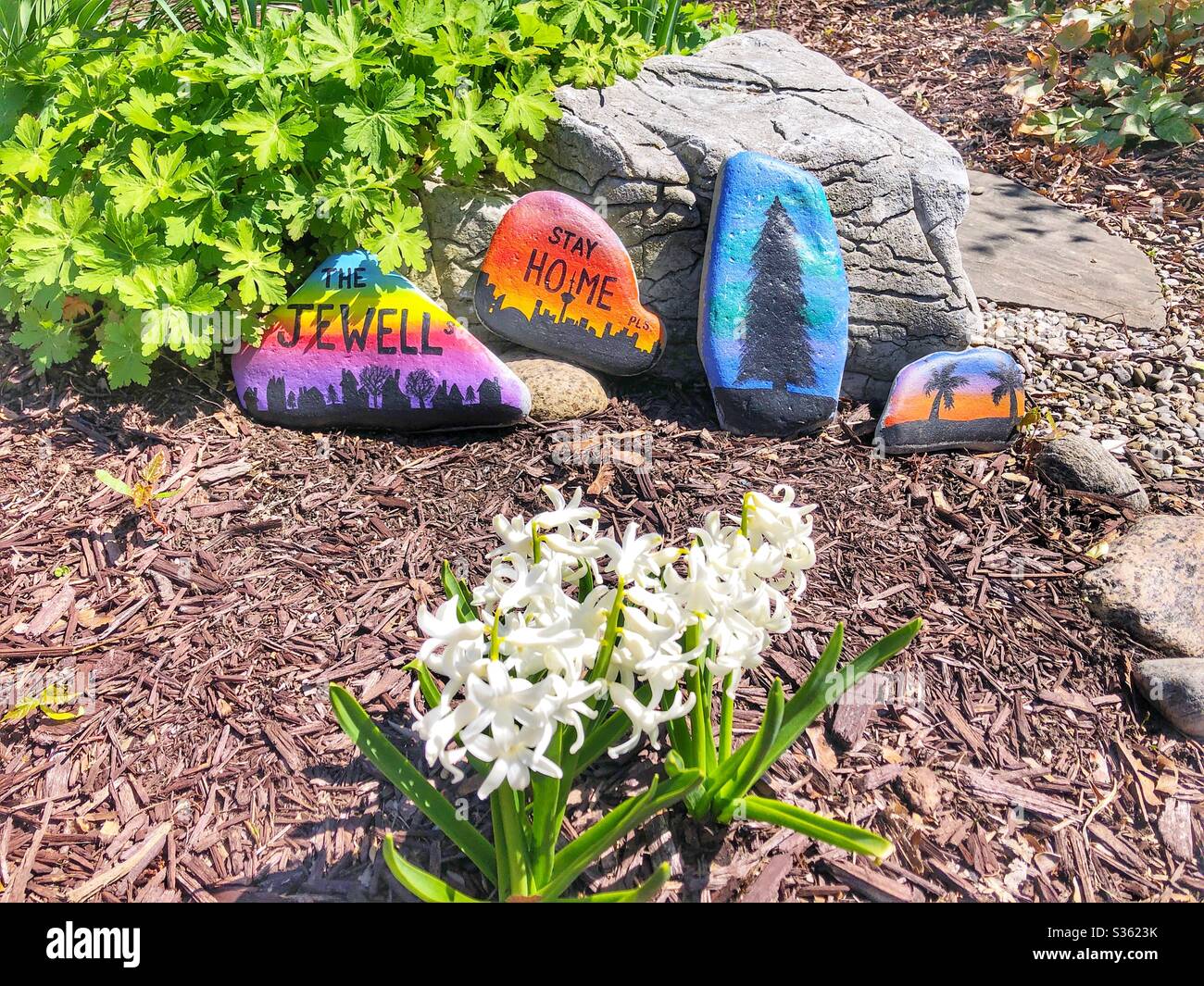 Bunt bemalte Steine schmücken einen Garten. - Smartphone-aufgenommenes Stockfoto