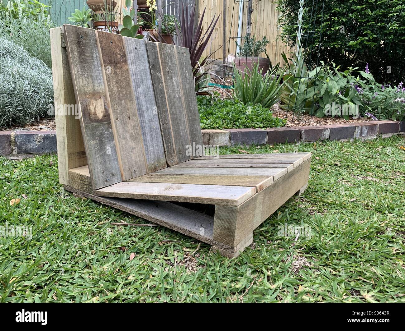 Ein Covid-19 Coronavirus-Heimprojekt, ein handgebauter Gartensitz, der aus alten, hochgetaktenen Holzzäunungsmaterialien gefertigt wurde - Smartphone-aufgenommenes Stockfoto
