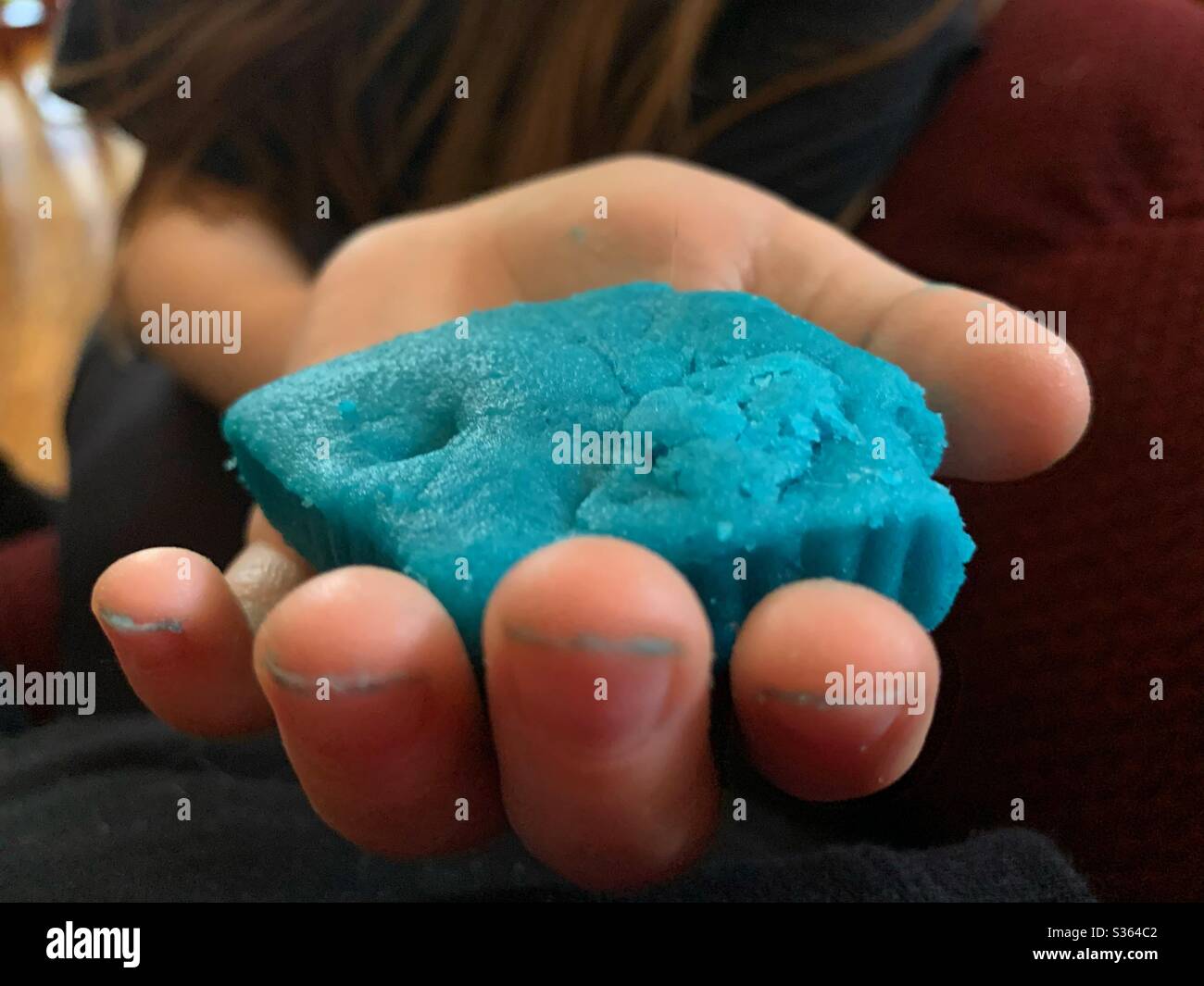 Nahaufnahme der Hand eines Kindes, die einen Bund von blauen hausgemachten Spielteig hält. Stockfoto