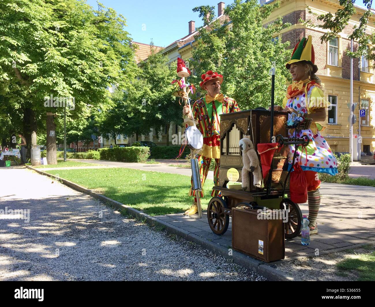 Maria und Alexander, zwei Straßenmusiker, die eine Deleika-Fassorgel spielen, die wie Clowns gekleidet ist, Sopron, Ungarn Stockfoto