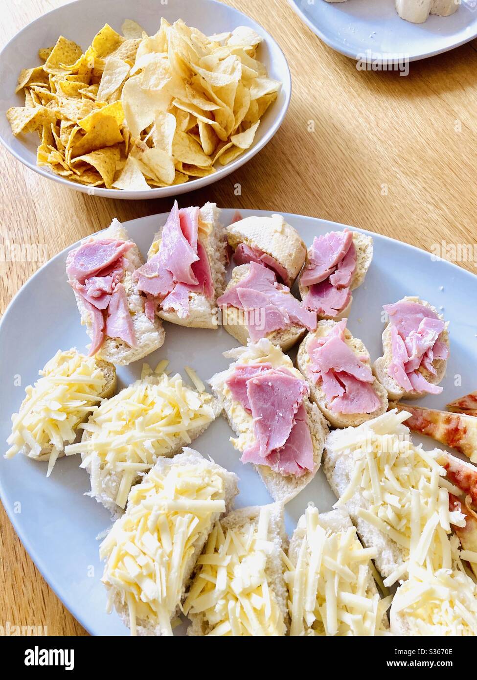 Kleine Sandwiches mit Schinken und Käse und einer Seite Tortilla Chips Stockfoto