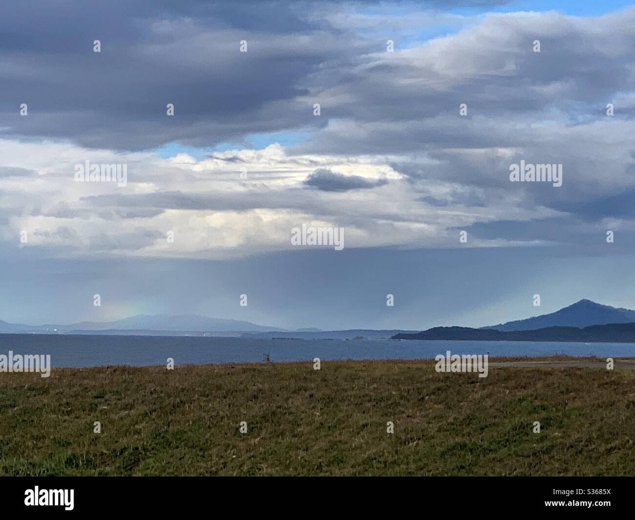 Landschaft mit Blick über das Meer zu einem Regenbogen - Smartphone-aufgenommenes Stockfoto