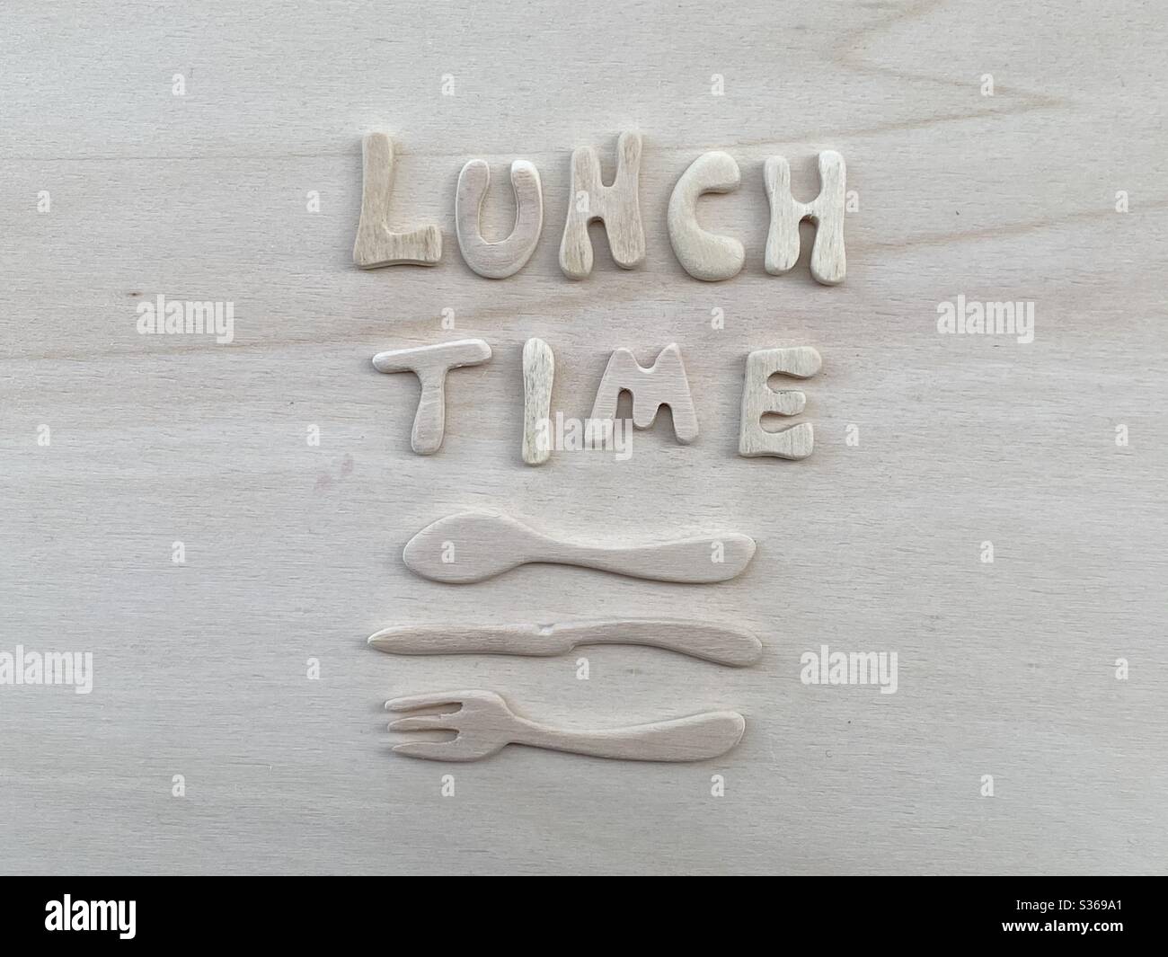 Mittagstext mit künstlerischen Holzbuchstaben mit Holzgabel, Messer und Löffel-Design auf einem Holzbrett Stockfoto