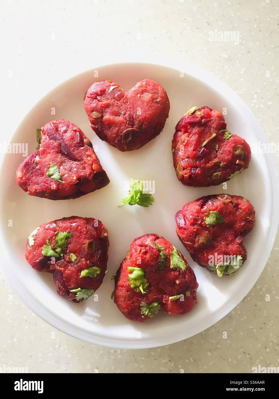 Hausgemachtes Gemüseschnitzel in Herzform arrangiert & in einen weißen Teller gelegt - Pre Cook veg Cutlet ein indischer Snack Stockfoto