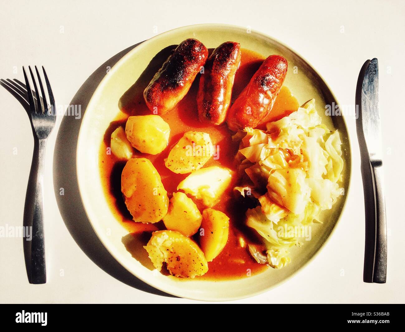 Schweinefleisch Würstchen gekochte Kartoffeln und Kohl mit Soße - Smartphone-aufgenommenes Stockfoto