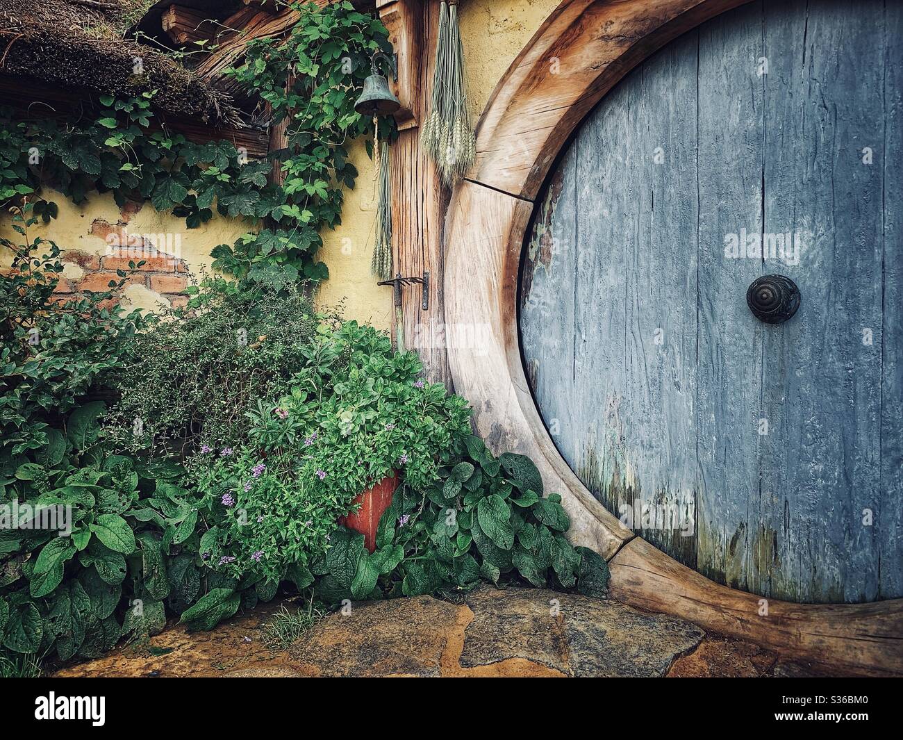 Hobbiton. Bukolischer Ort in Neuseeland, wo die Hobbits aus der Mittelerde leben. Lord of the rings Filmset. Blaue Holztür Stockfoto