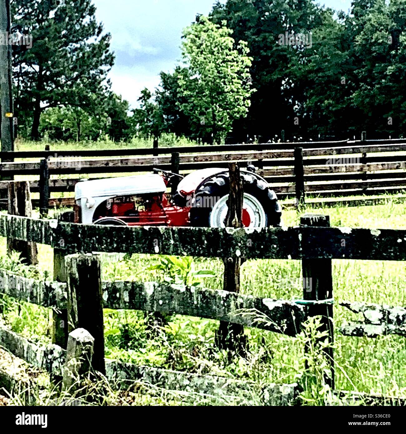 Little Red and White Traktor hinter Zaun, draußen auf dem Land in South Carolina Stockfoto