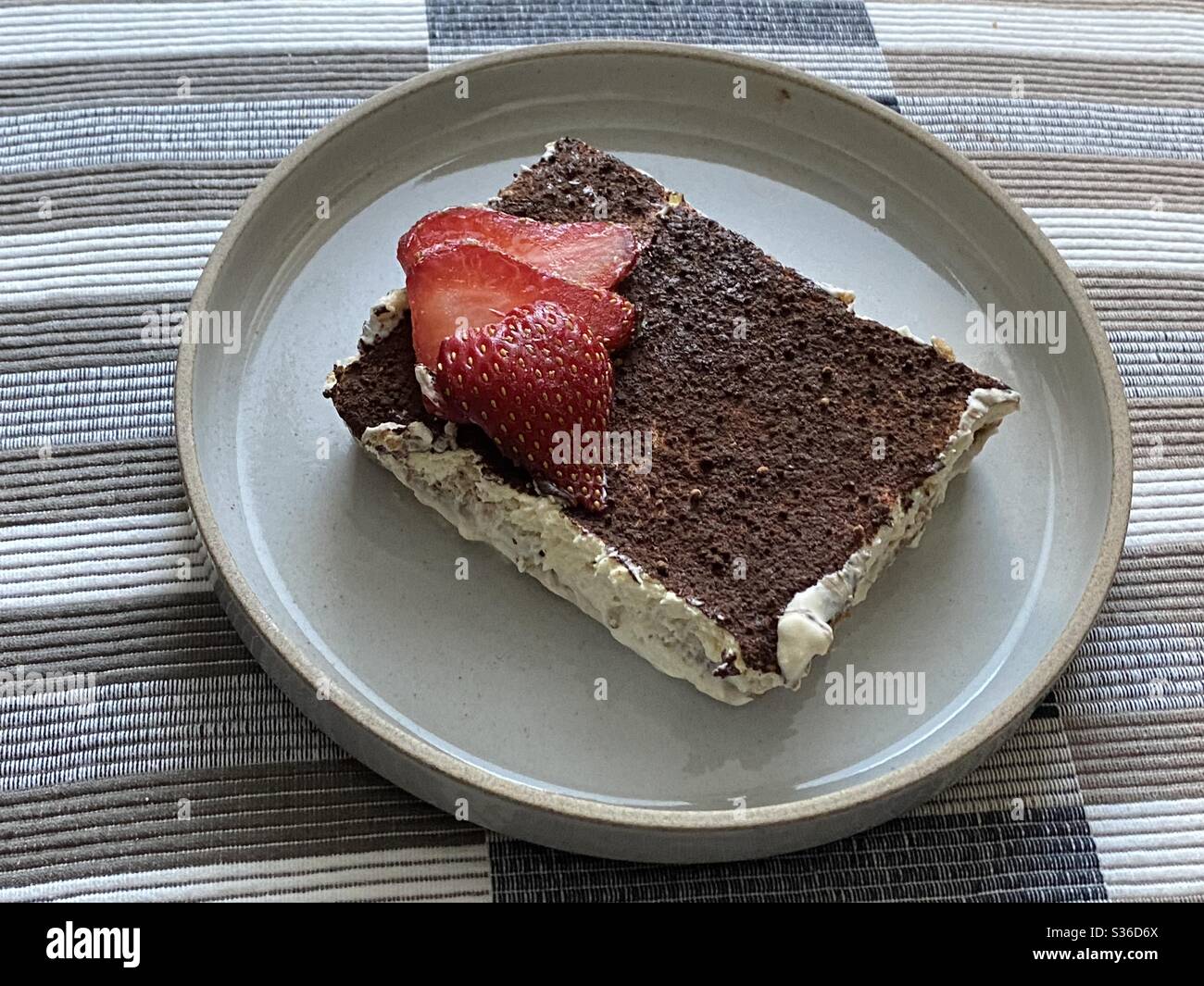 Tiramisu, italienisches Dessert mit Kaffeegeschmack, mit in Kaffee getauchten Schwammfingern, mit einer Mischung aus Eiern, Zucker und Mascarpone-Käse, mit Kakao gewürzt. Gekrönt mit Erdbeere in Scheiben Stockfoto