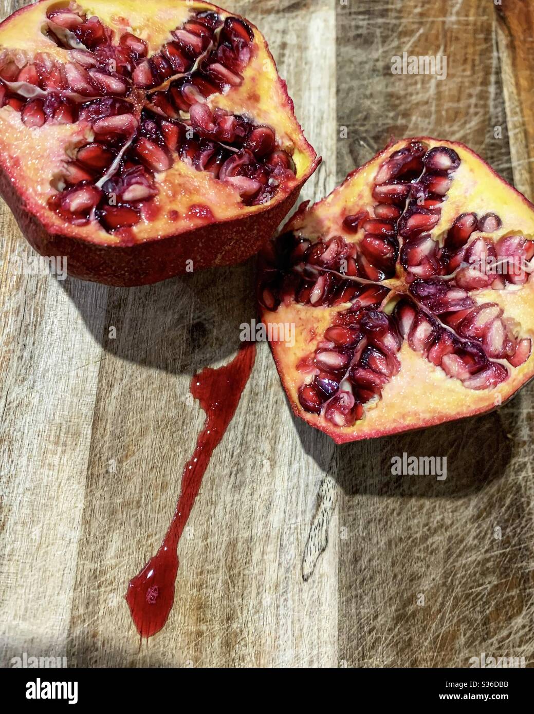 Frucht, saftig reifer Granatapfel, halbiert, zeigt rosafarbene essbare Samen oder Arillen - Smartphone-aufgenommenes Stockfoto