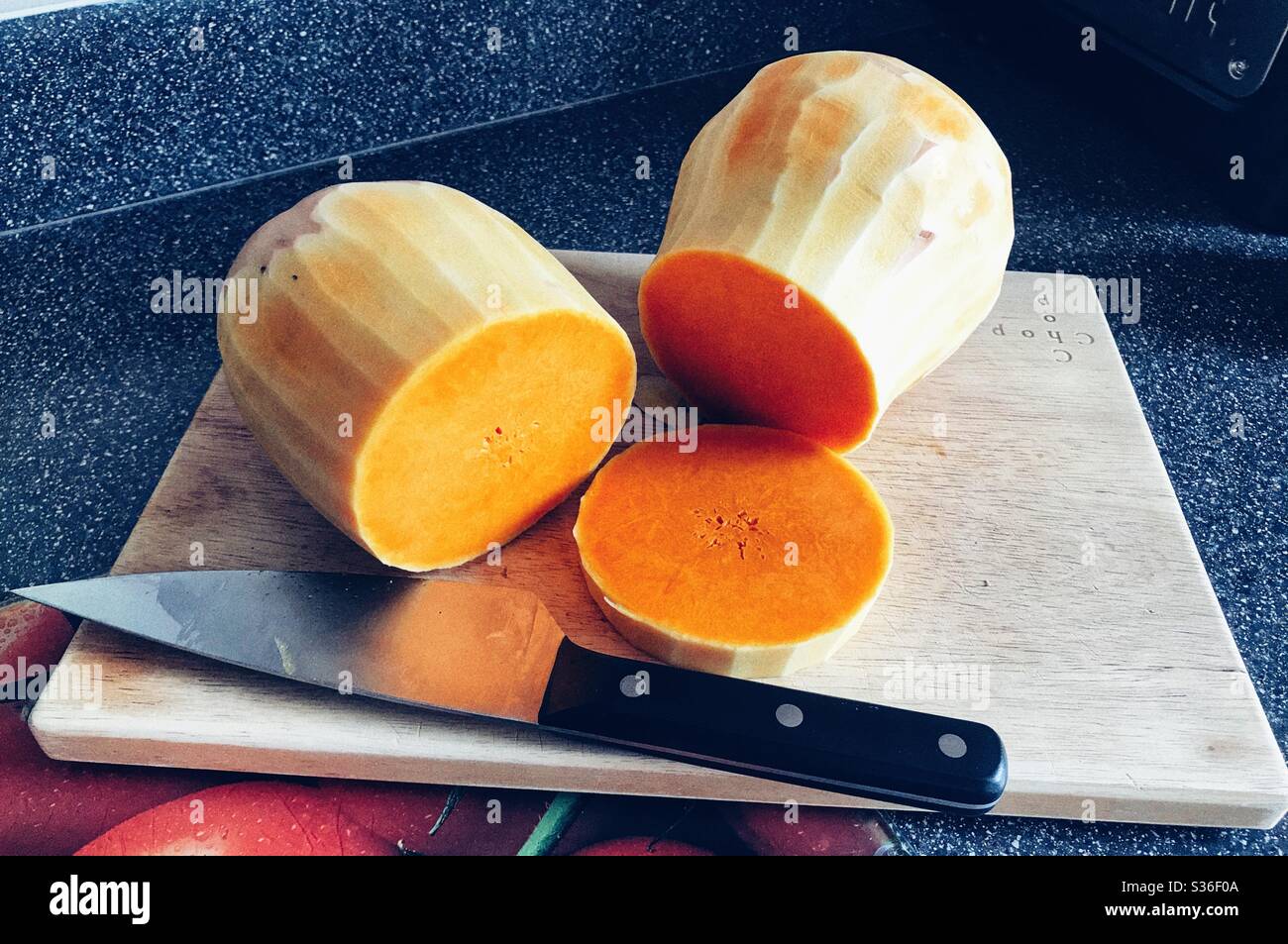 Butternut Squash und ein Messer auf einem Schneidebrett - Smartphone-aufgenommenes Stockfoto