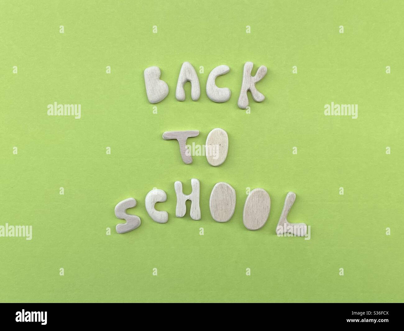 Zurück zur Schule mit handgefertigten Holzbuchstaben über grüner Farbe komponiert Stockfoto