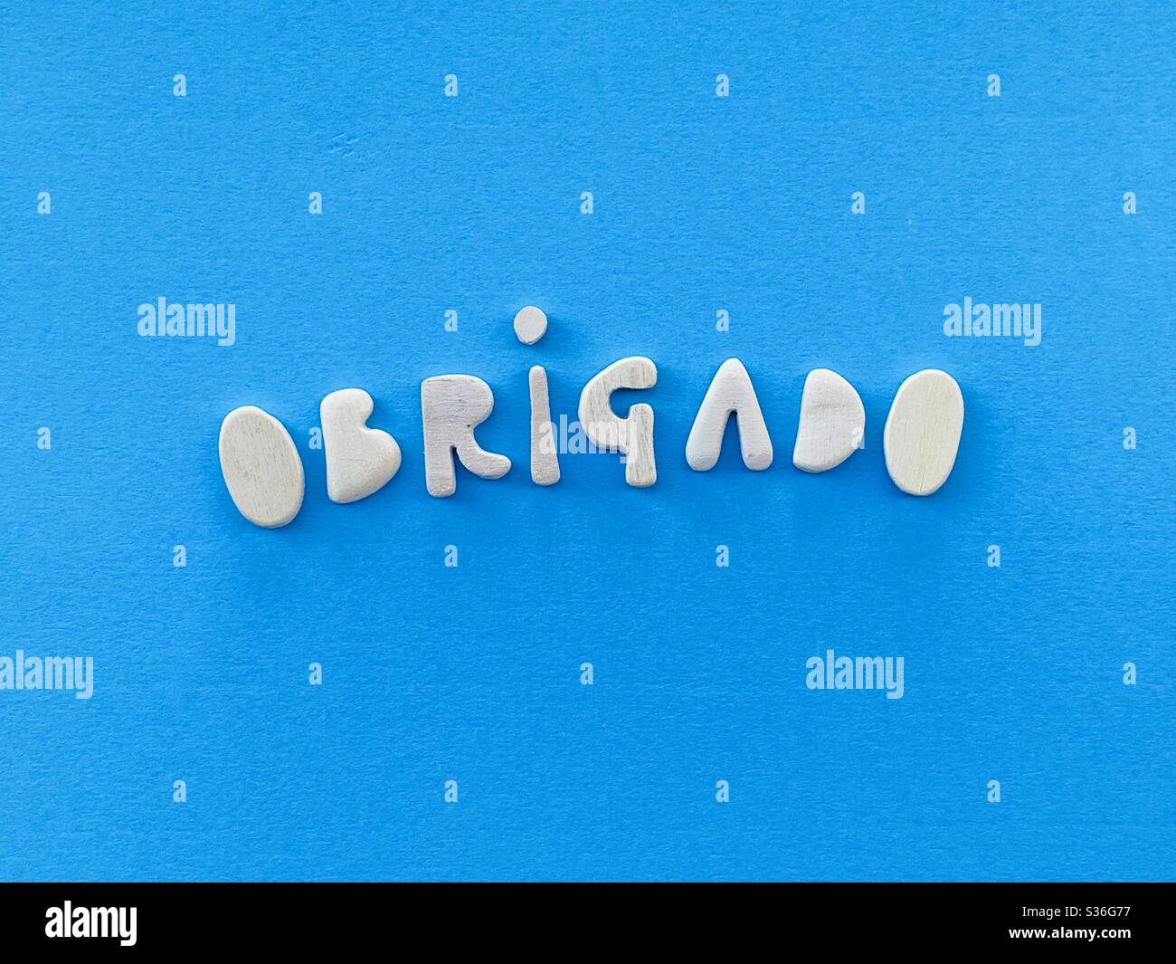 Obrigado, danke in potuguese Sprache mit handgefertigten Holzbuchstaben über blauer Farbe komponiert Stockfoto