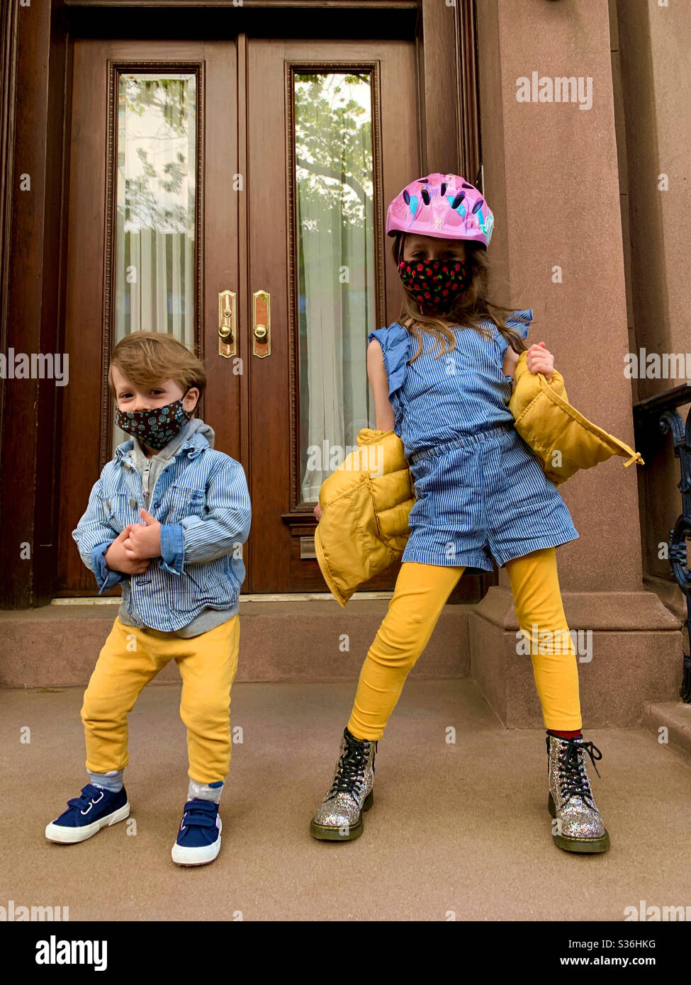 Bruder und Schwester „Fashionistas“ während der Pandemie-Quarantäne posieren mit Masken auf ihren vorderen Stufen in Brooklyn, N.Y.cheering auf den Krankenschwestern. - Smartphone-aufgenommenes Stockfoto