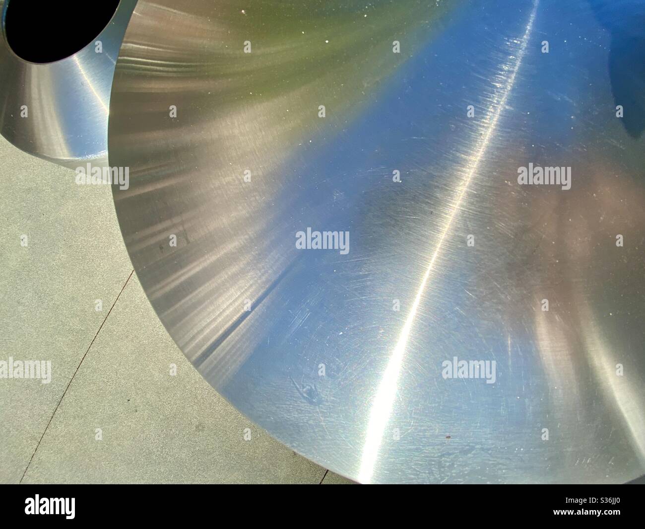 Die Platten aus runden, gebürsteten Edelstahlbehältern schufen abstrakte Komposition und Hintergrund auf Betonpflaster Stockfoto