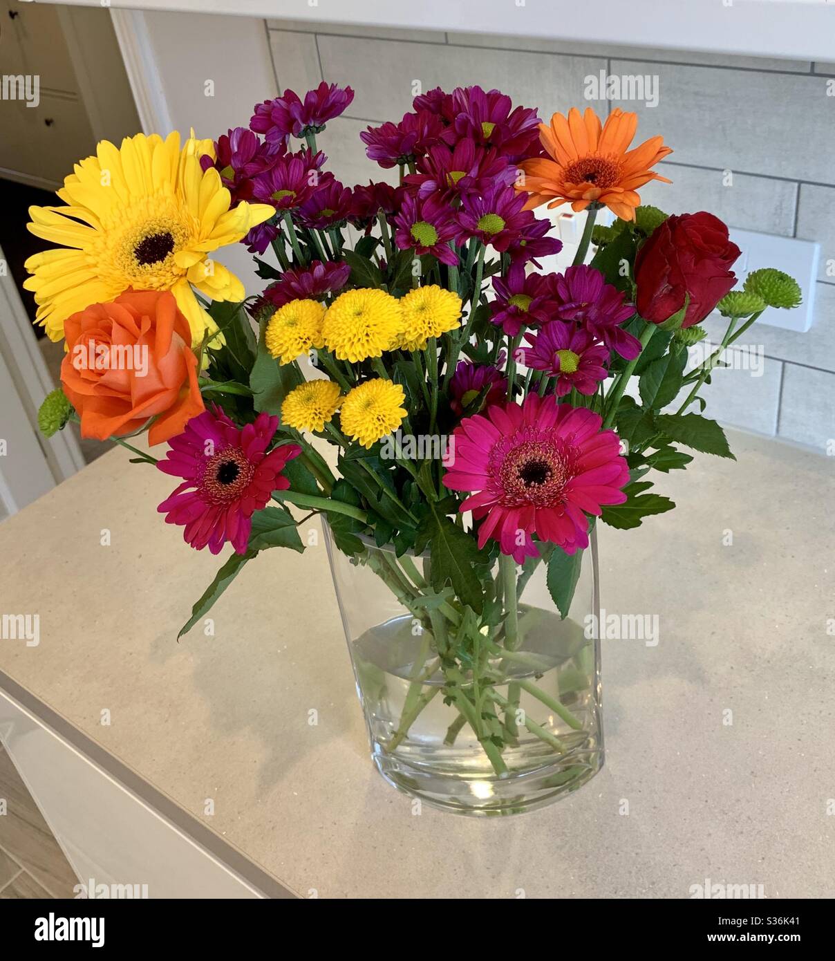 Bunte Blumenstrauß in einer Glasvase, saß auf einer Küchenarbeitsfläche. - Smartphone-aufgenommenes Stockfoto
