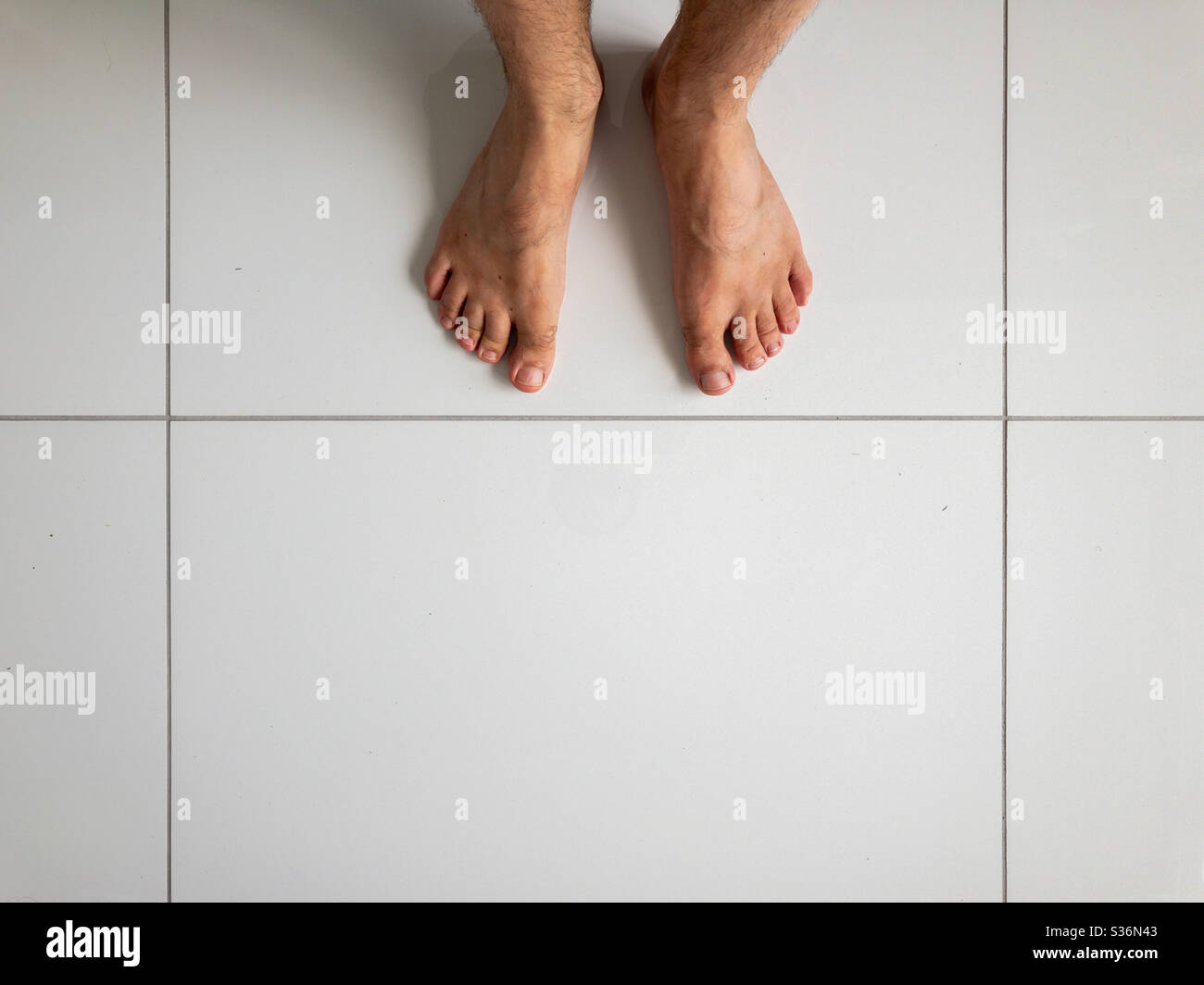 Die Füße des Menschen auf weißen Keramikfliesen Stockfoto