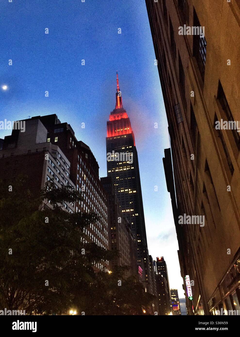 Das Empire State Building ist an einem nebligen Abend in NYC, USA, mit roten Lichtern beleuchtet Stockfoto