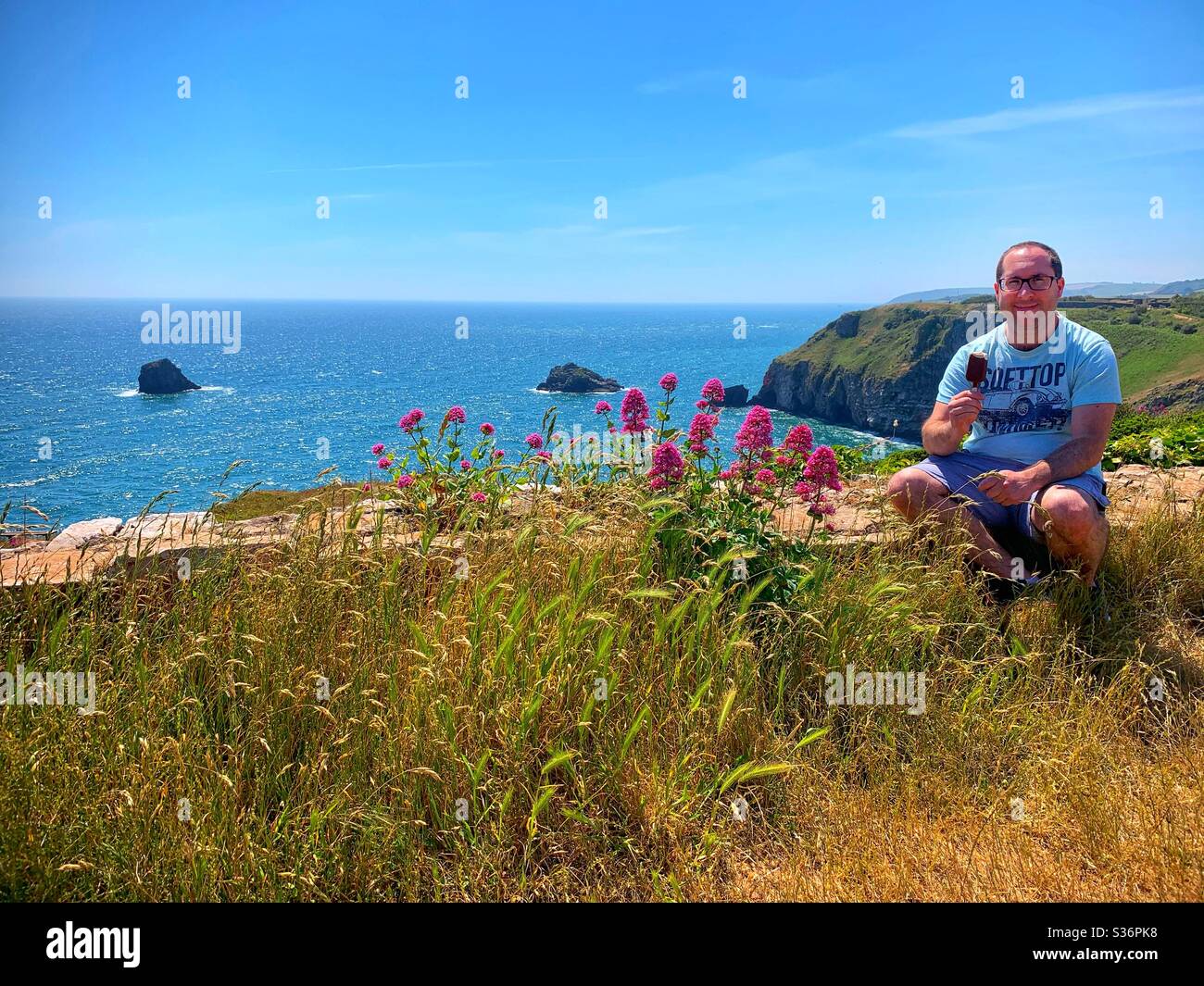 Mann, der ein Magnum-Eis vor einer wunderschönen Kulisse mit Meerblick isst. Berry Head, Brixham, Devon. - Smartphone-aufgenommenes Stockfoto