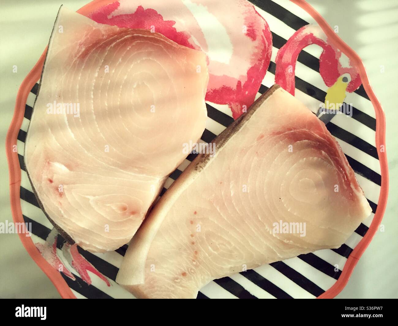 Nahaufnahme von zwei frischen rohen Schwertfisch-Steaks auf einem Kitch Flamingo-Teller, USA Stockfoto
