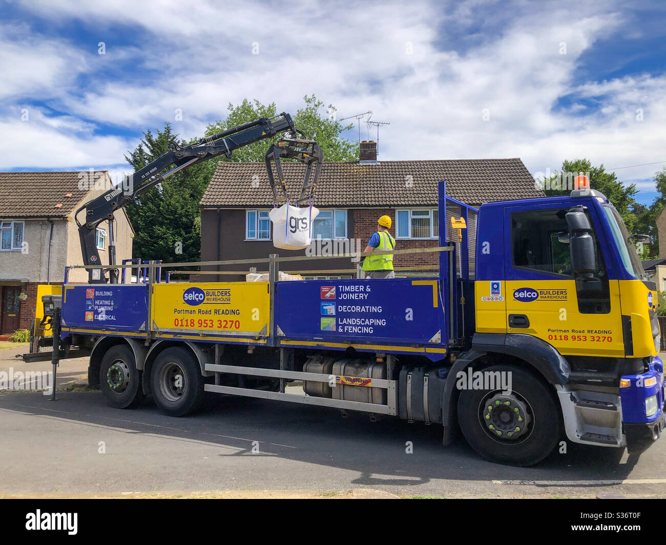 Ein SELCO Bauunternehmer Lieferwagen liefert eine Tüte Kies zu einem Haus. - Smartphone-aufgenommenes Stockfoto