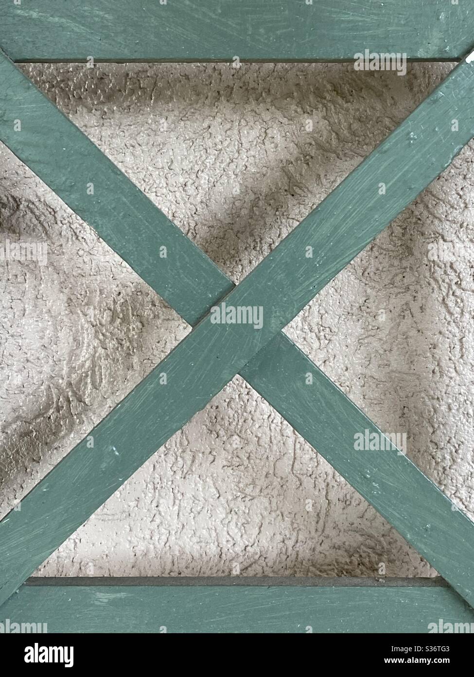 Grüner Buchstabe X vor einem neutralen Wandhintergrund Stockfoto