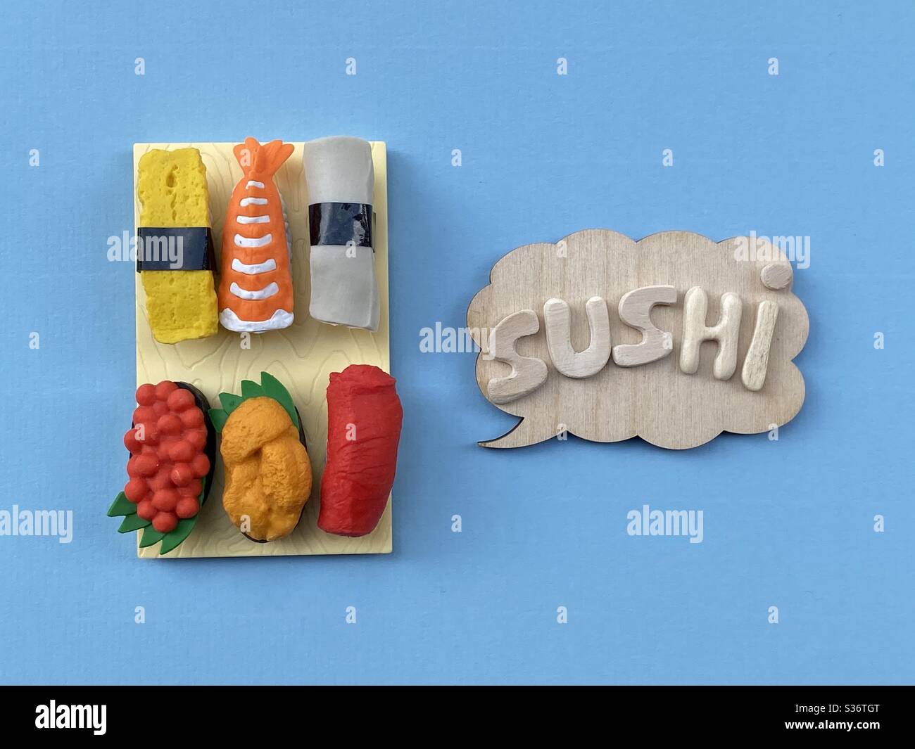 Sushi, konzeptuelle Komposition mit Holzbuchstaben und japanisches Essen über blauer Farbe - Smartphone-aufgenommenes Stockfoto