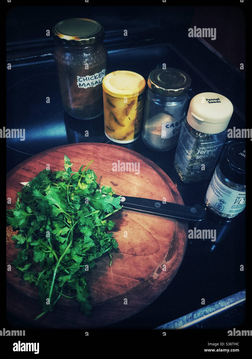 Schneidebrett mit Koriander und Gewürzsammlung. - Smartphone-aufgenommenes Stockfoto