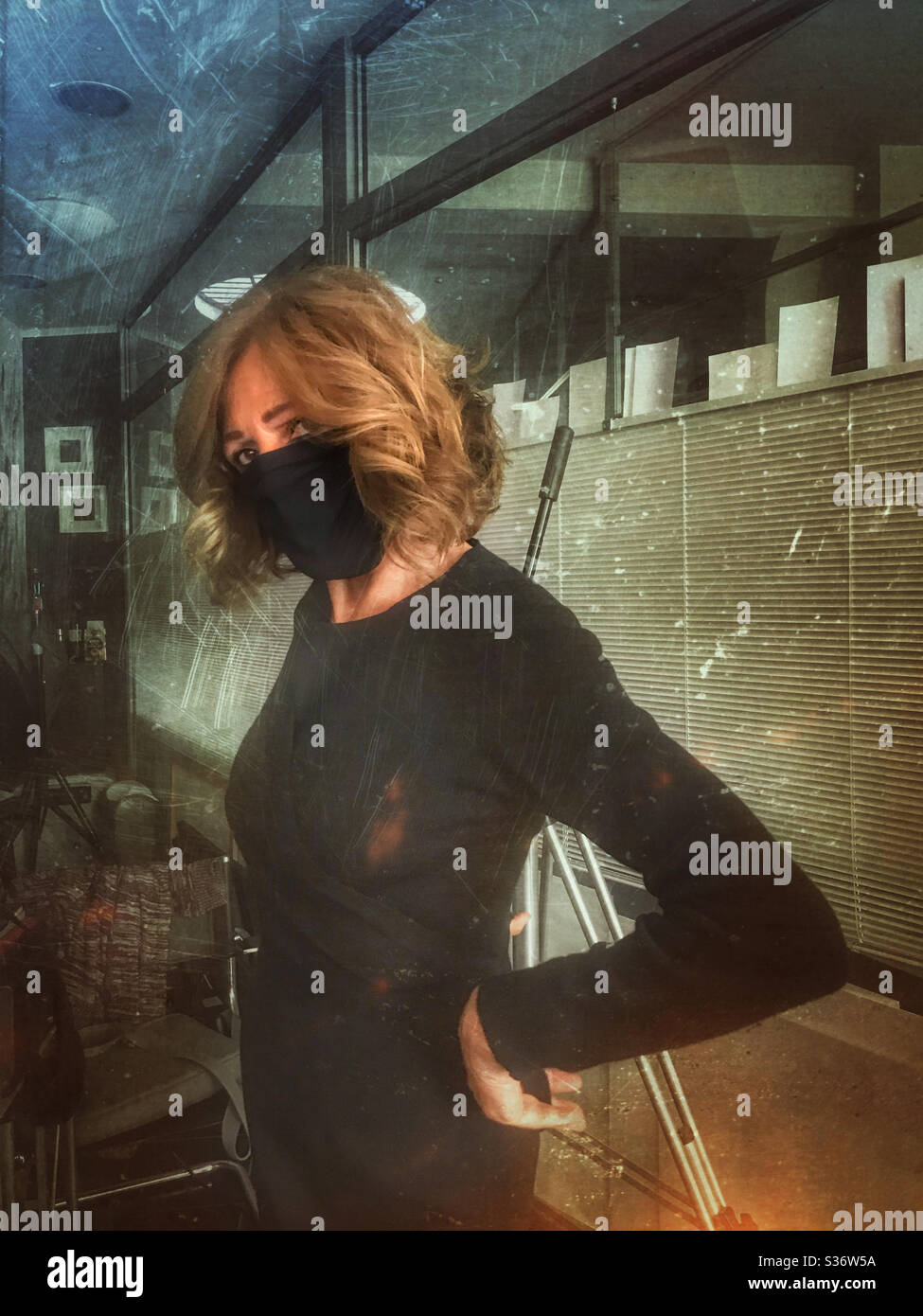 Elegante schwarze Dame trägt schwarze Gesichtsmaske zum Schutz im Büro bei der Arbeit Stockfoto