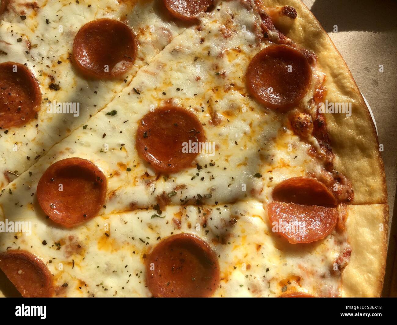 Pizza an einem sonnigen Fenster mit Schatten Stockfoto