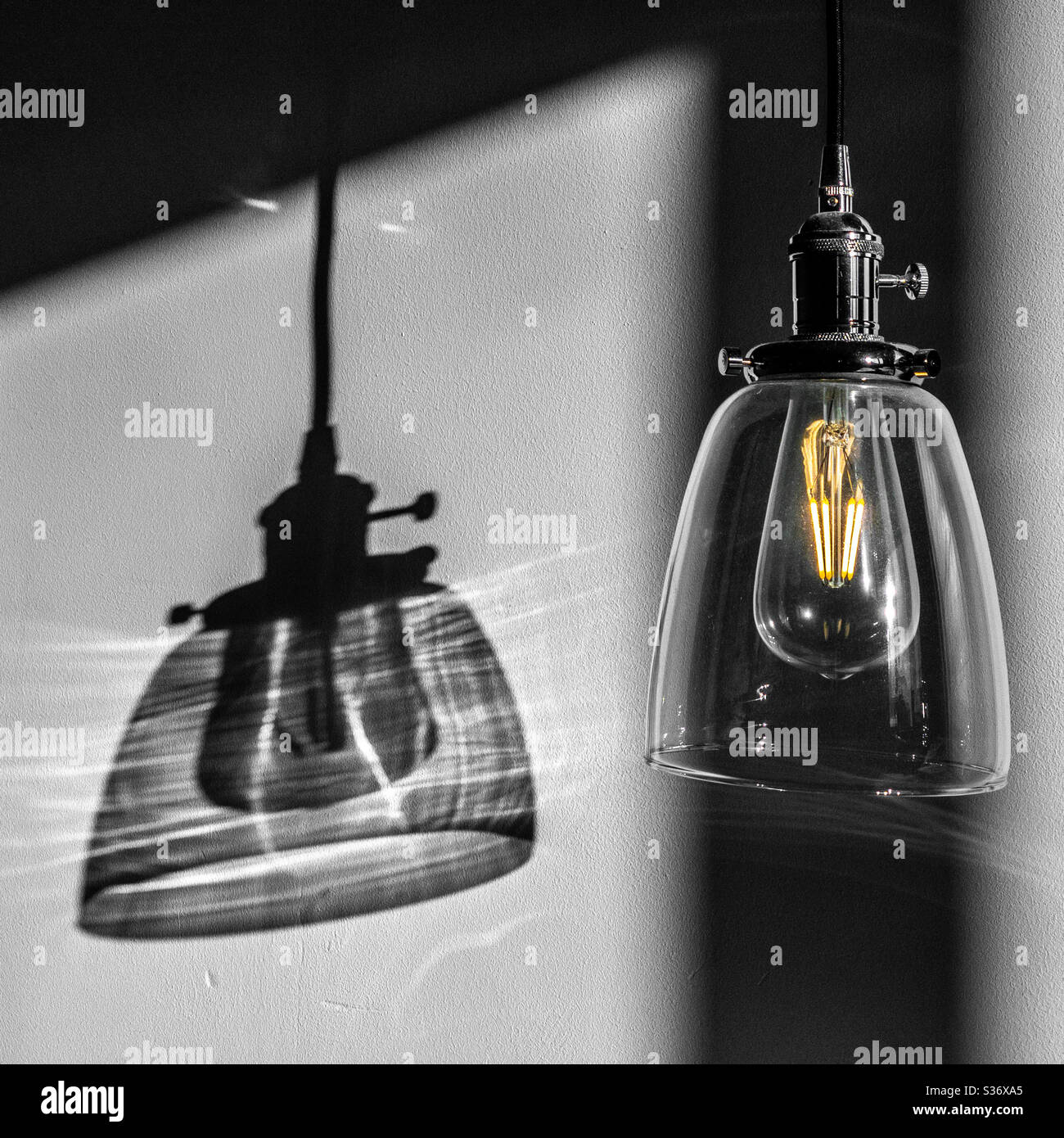 Hängender Lampenschirm aus Glas mit LED Glühbirne und Schatten an der Wand Stockfoto