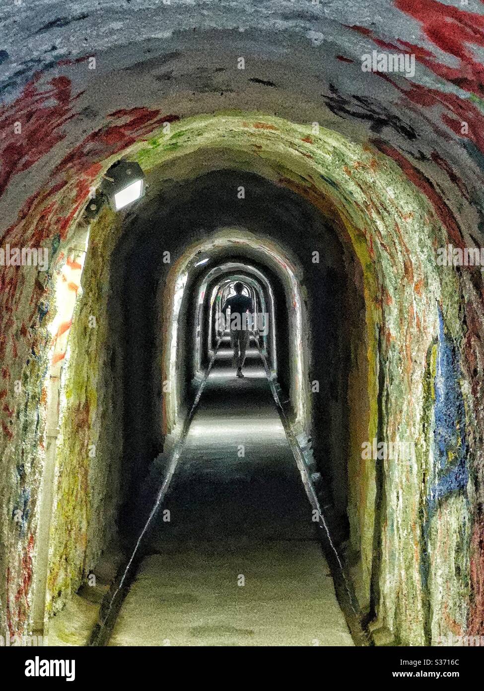 Mann läuft durch Fußgängertunnel mit Graffiti - Smartphone-aufgenommenes Stockfoto