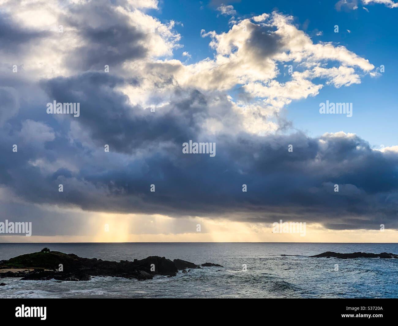 Sonnenlicht strömt durch die Wolken über den Ozean Stockfoto