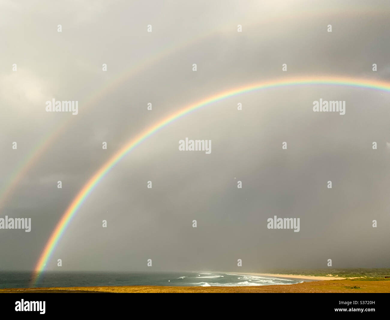 Doppelter Regenbogen über Meer und Strand und Wellen, Lichtbrechung, Natur, NSW Australien Stockfoto