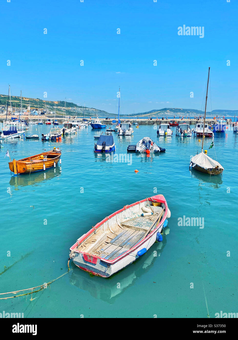 Boote im ruhigen und malerischen Lyme Regis Hafen, Dorset, England. Ein Ort, der sowohl für Ferien als auch für historische Bedeutung berühmt ist - an der Jurassic Coast gelegen, berühmt für fossile Überreste Stockfoto