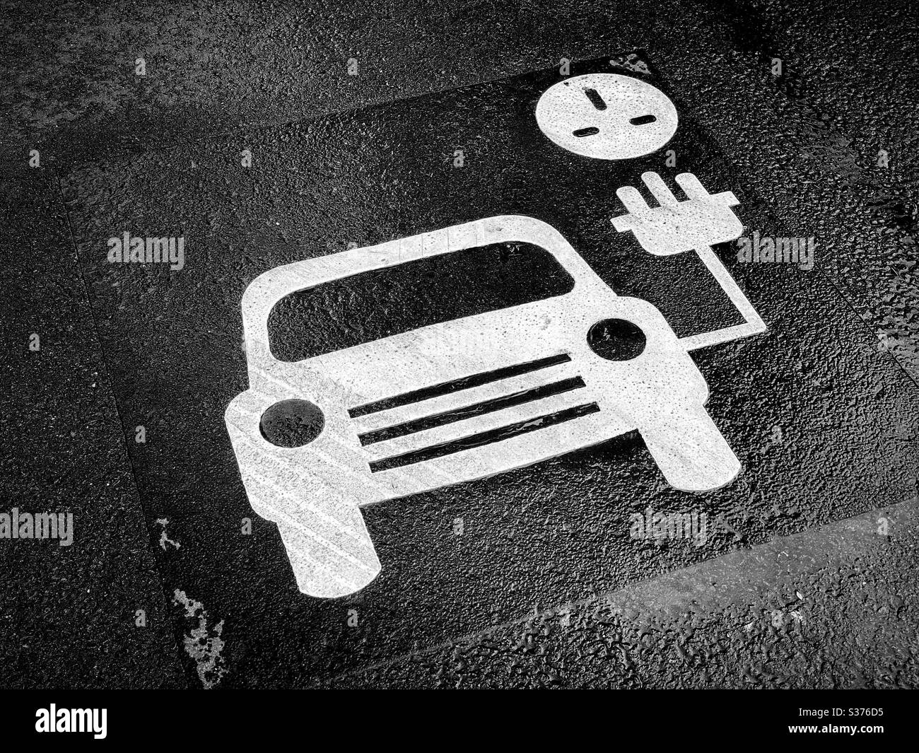 Ein Schild in einem Parkplatz, das diesen Bereich anzeigt, ist für das Aufladen der Batterien von Elektrofahrzeugen bestimmt. CO2-Emissionen schaden der Umwelt. Die Zukunft ist erneuerbare Energie! Foto ©️ COLIN HOSKINS. - Smartphone-aufgenommenes Stockfoto