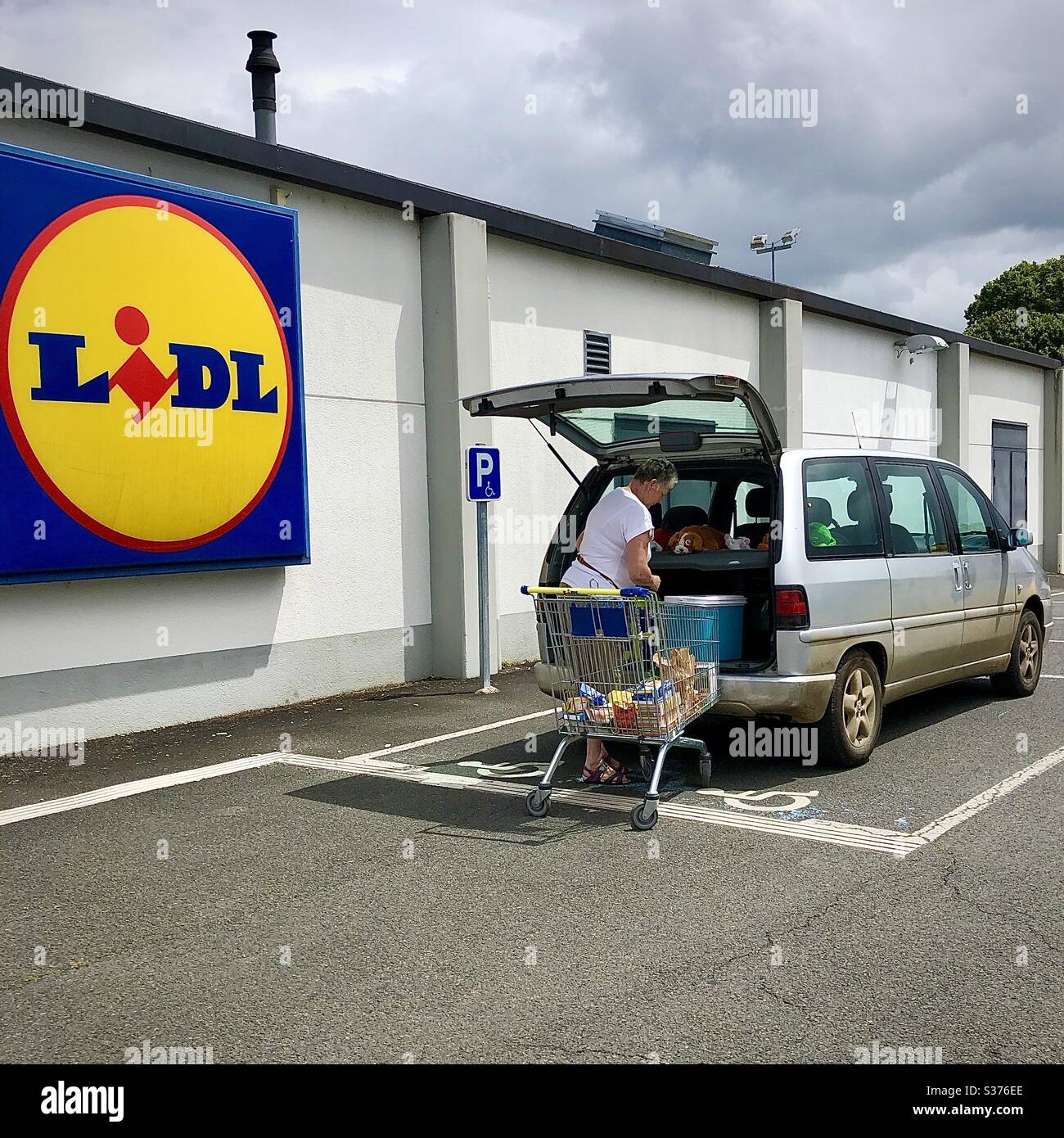 Laden von Geschäften in ein Auto außerhalb des LIDL-Stores, Frankreich. - Smartphone-aufgenommenes Stockfoto