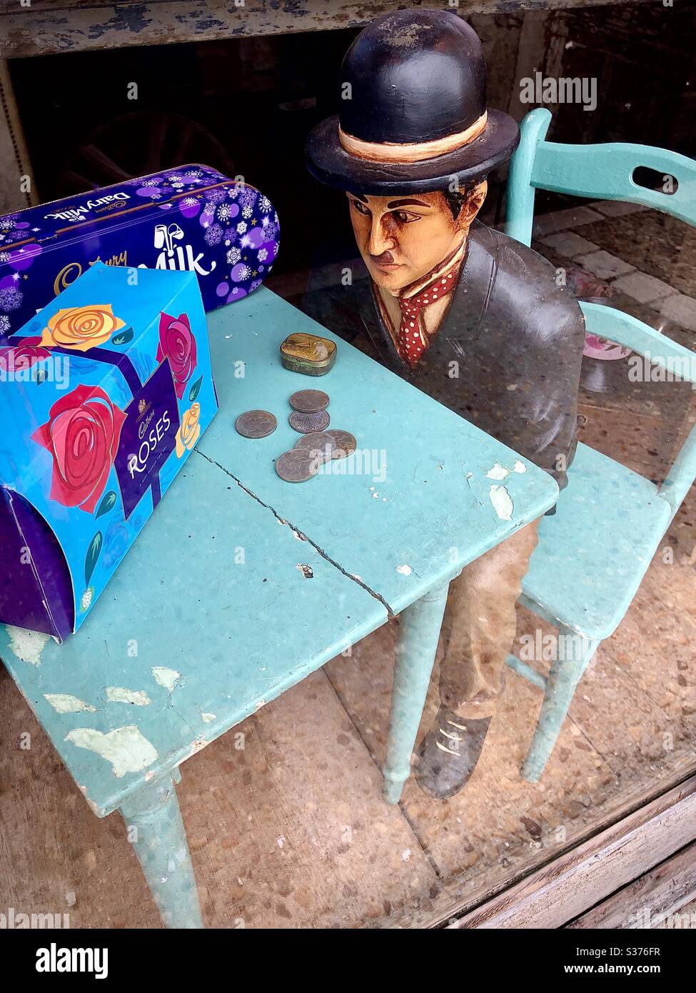 Miniaturmaquette des Mannes, der am Tisch im süßen Schaufenster sitzt, Le Blanc, Indre, Frankreich. - Smartphone-aufgenommenes Stockfoto