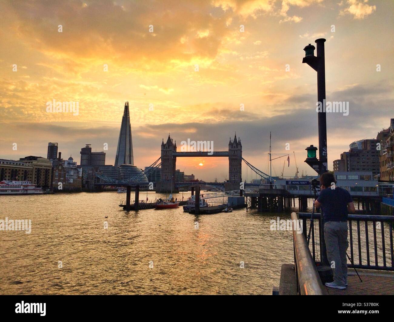 Ein Mann fotografiert einen Blick auf die Tower Bridge und den Shard Wolkenkratzer bei Sonnenuntergang auf der Themse - Smartphone-aufgenommenes Stockfoto