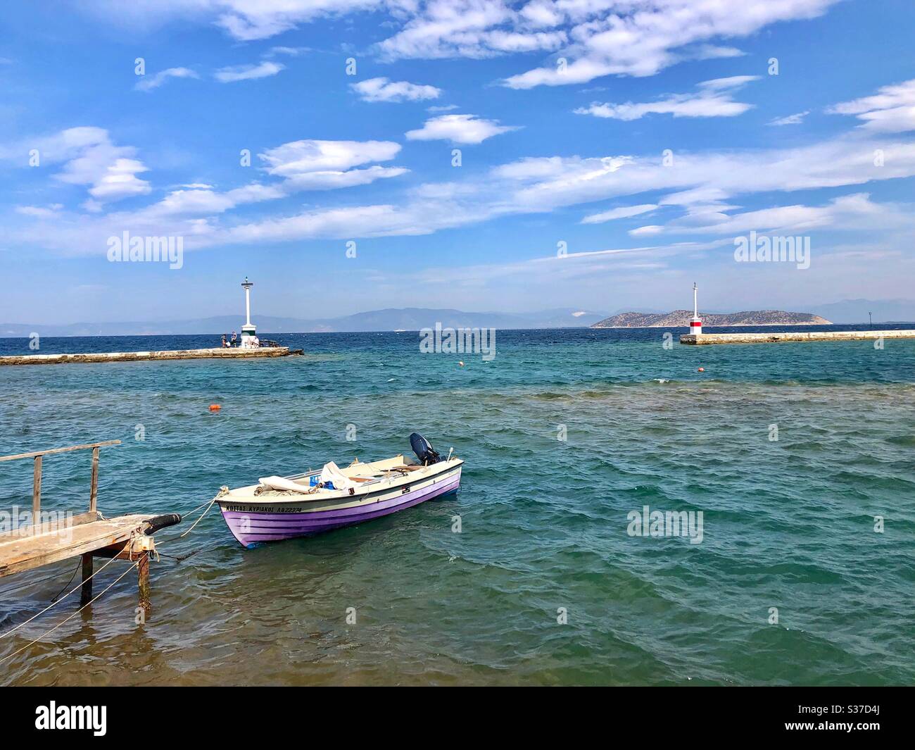 Blick auf Leuchttürme mit violettem Boot vor dem alten Hafen von Limenas, der Hauptstadt der Insel Thassos in Griechenland. - Smartphone-aufgenommenes Stockfoto