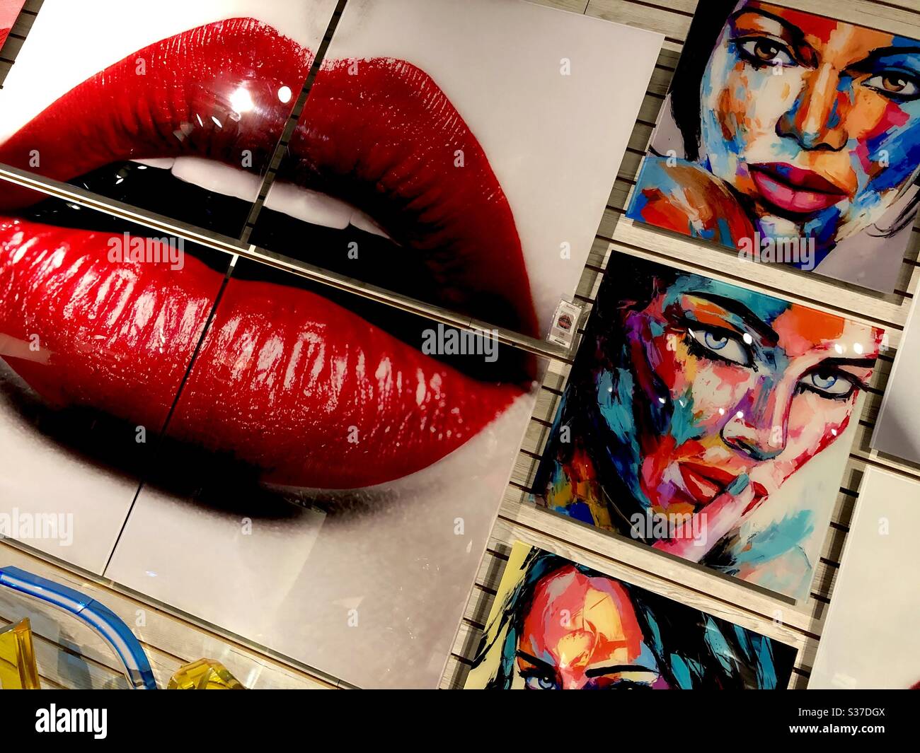 Moderne Kunstwerke in einem Möbelraum mit Frauenmund mit rotem Lippenstift und mehreren abstrakten Porträts. Stockfoto
