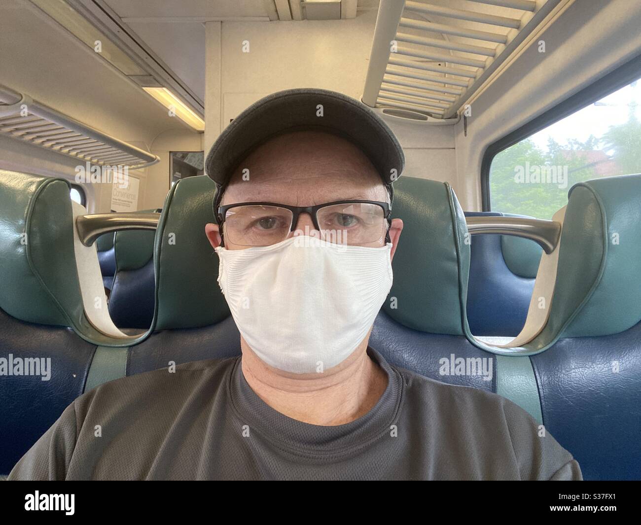 Eineiiger älterer Mann mit Gesichtsmaske, im Pendlerzug während der covid-19 Pandemie Lockdown in New York City. Stockfoto