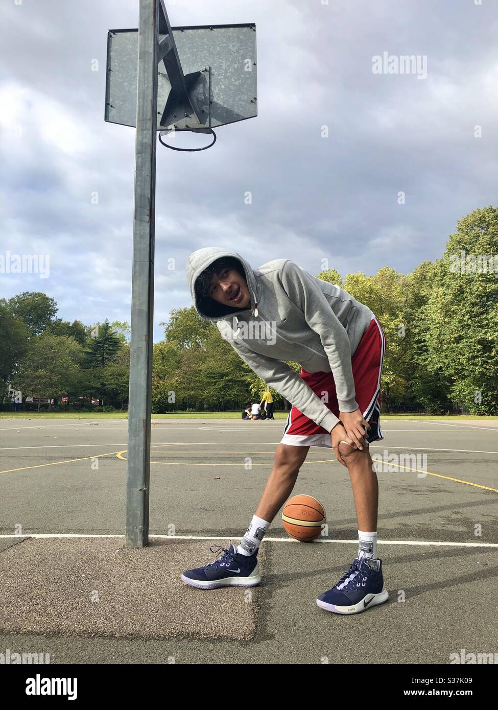 Junger Mann, der sich aufwärmt, um auf einem Platz in London Basketball zu spielen Stockfoto