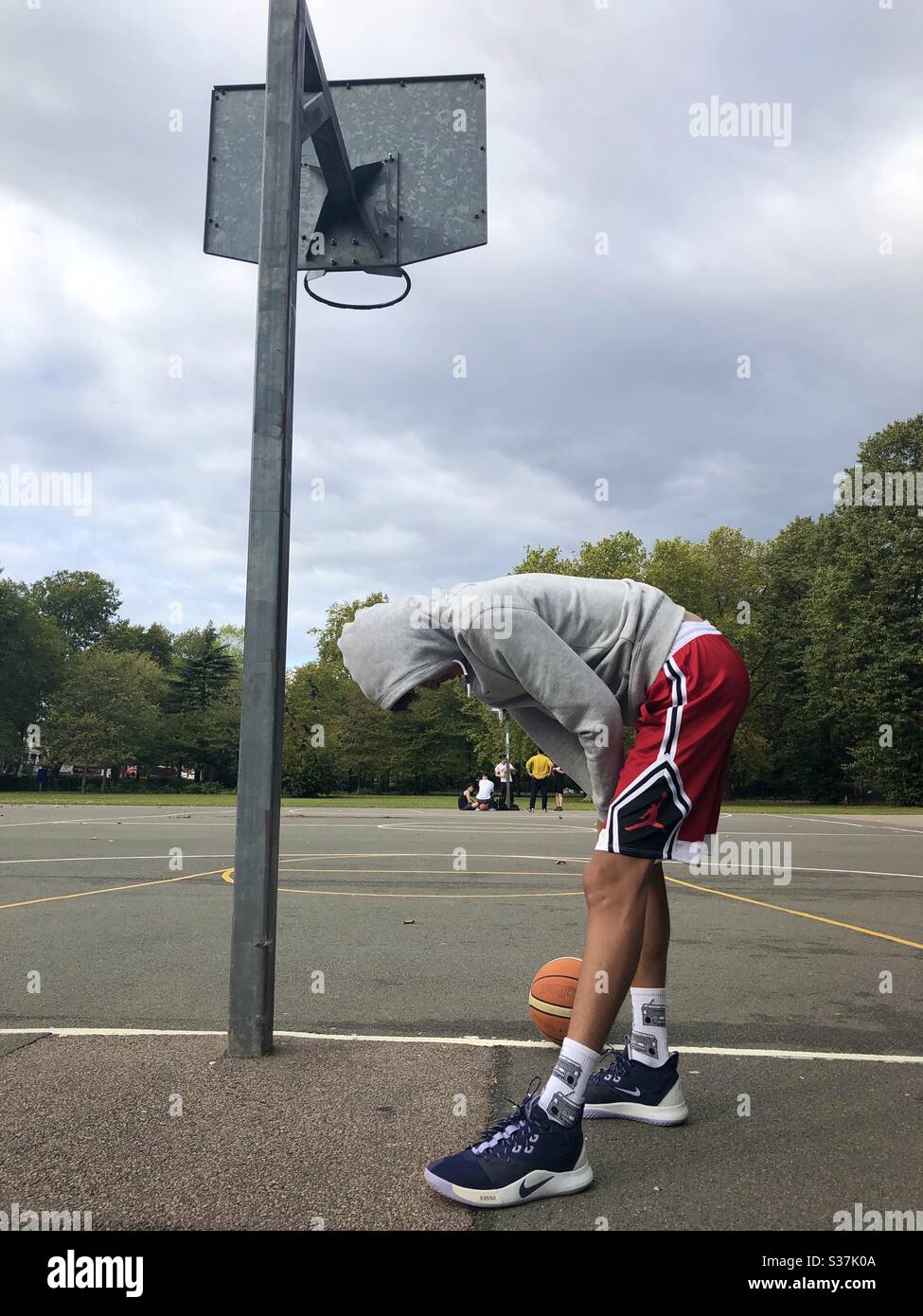 Junger Mann, der sich aufwärmt, um auf einem Platz in London Basketball zu spielen Stockfoto