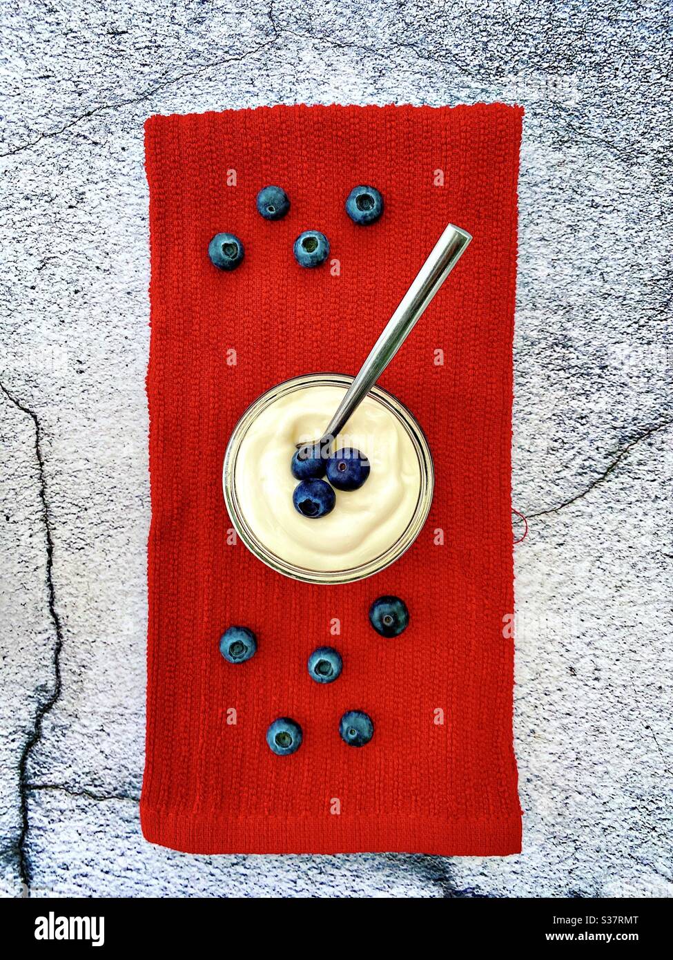 Frische Heidelbeeren und Joghurt vor einem natürlichen Granit-Hintergrund. Gesunde Sommerbeeren voller Antioxidantien. Essen auf der Küchenabtheke. Stockfoto