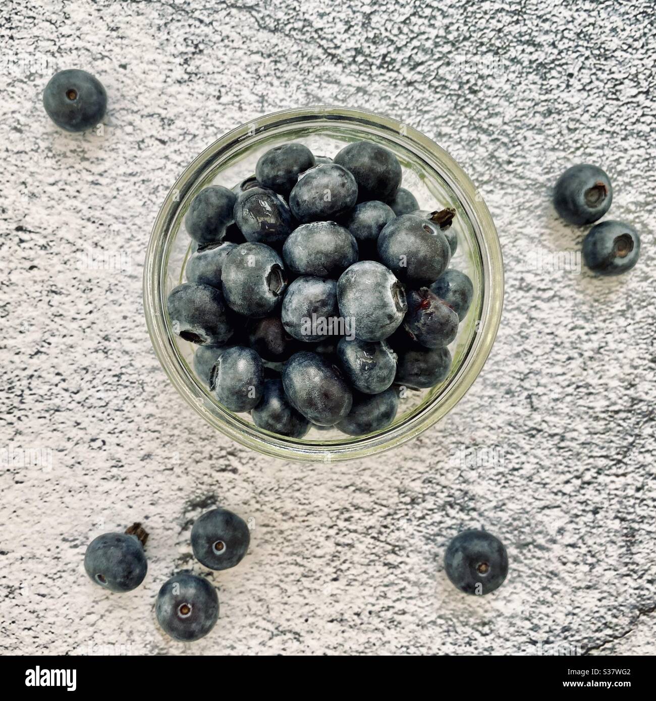 Nahaufnahme von frischen Blaubeeren in einer kleinen Glasschüssel gegen eine natürliche Granitplatte in der Küche. Saftige Beeren voller Antioxidantien - Smartphone-aufgenommenes Stockfoto