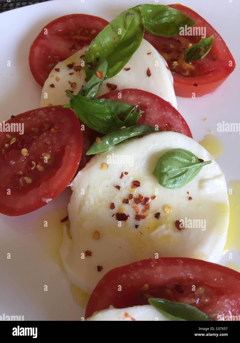 Stillleben eines Salats von Mozzarella-Käse Scheiben, frisches Basilikum, Rebe reife Tomaten in einer würzigen Olivenöl Mischung bedeckt Stockfoto