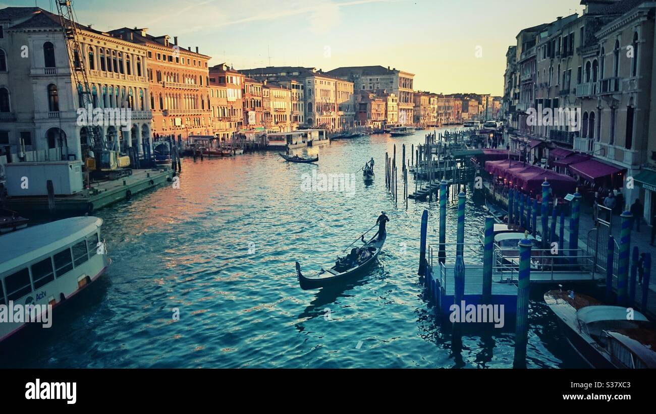 Ein Foto von Gondeln und einem Wasserbus (Vaporetto) auf dem Canal Grande in Venedig, Italien, bei Sonnenuntergang, von der Rialtobrücke. Europäisches Reiseziel. Stockfoto